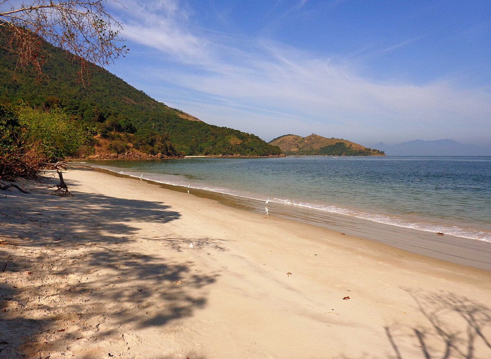 Faixa de areia clara, água calma e montanhas cobertas por Mata Atlântica na Marambaia