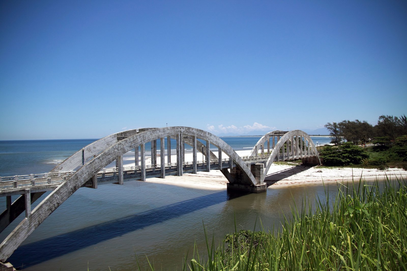 Ponte de madeira antiga sobre água tranquila na Marambaia